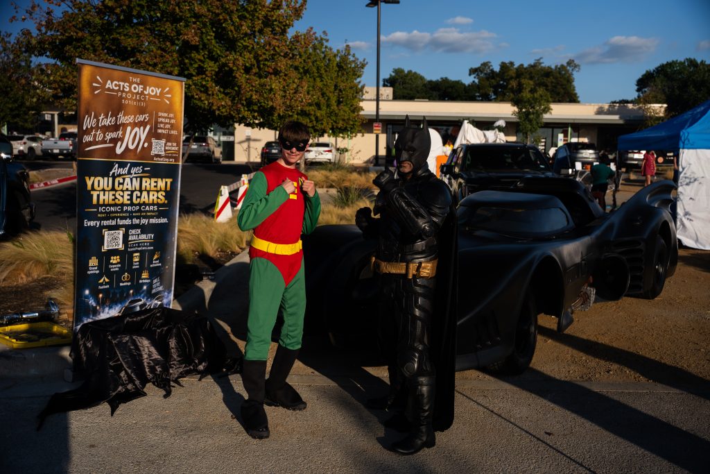 Batman and Robin characters with the Batmobile and an event banner at Trunk or Treat, Lake Ridge Village