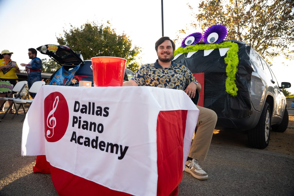 Dallas Piano Academy host at a decorated trunk with a purple monster display at Trunk or Treat