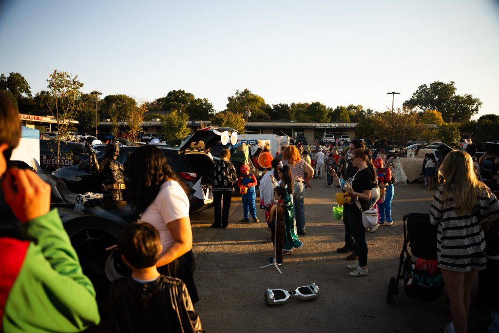 Wide view of families walking past decorated trunks at sunset, Lake Ridge Village Trunk or Treat